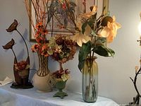 Wide view showing all four faux flower arrangements on a table under framed artwork