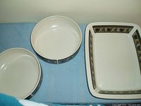 Two round cream-colored serving bowls with a band of blue and green floral pattern on the outside next to a rectangular serving dish with a similar floral patterned border around the rim