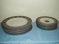 Stack of 8 dinner plates with decorative floral and leaf pattern border and 8 sandwich plates with single floral motif stack beside them