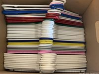 Top view of a packed box showing multiple plastic hangers in a variety of colors stacked flat.