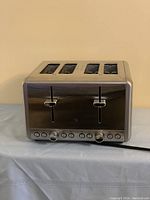Front view of a 4-slice stainless steel toaster with controls and buttons on the front panel.