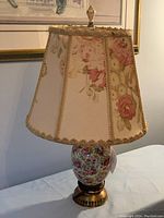 Full view of the lamp with fabric rose floral shade and ceramic base with rose pattern on a brass base.