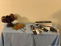 Image showing decorative balls on a stand, metal maple leaf wall hangers, and paint sample booklets on a table covered with a light blue cloth.