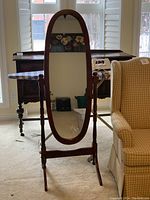 Full view of the oval wood framed mirror showing entire frame, base, and legs in a standing position.