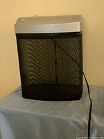 Photo of Fellowes P50CM paper shredder with black mesh bin on blue surface.
