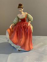 Front view of the Royal Doulton Fair Lady figurine showing red dress, green puffed sleeves, and detailed hairstyle.
