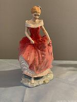 Front view showing detailed front of figurine with woman in red dress lifting skirt.