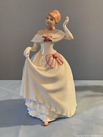 Front view of Royal Doulton Dawn porcelain figurine featuring the woman in an off-shoulder white dress with pink floral details.