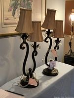 Front view of the set of two table lamps with fabric shades and metal base with scrolling design and crystal pendants.
