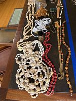 Multiple shell and beaded necklaces, assorted watches, and jewelry items arranged on table