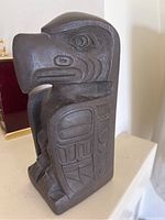 Frontal side image of the dark wood eagle carving statue displaying detailed indigenous patterns and stylized facial features.