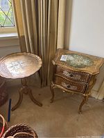 Photo of both side tables together, showing their relative size and position next to a window with cream curtains.