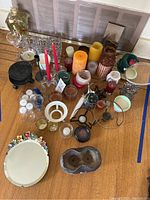 Overview of all items laid out on a table including candles, candle holders, the hanging wall mirror, and decorative display bottle