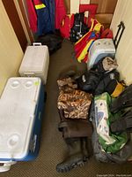Wide view showing two plastic coolers, electric cooler, waders and life jackets