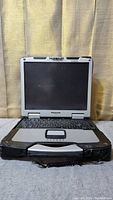 Front view of open Panasonic Toughbook CF-30 laptop showing screen, keyboard, and touchpad with rugged design and handle