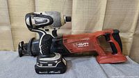 Hilti reciprocating saw and Makita impact driver placed side by side showing size comparison and condition