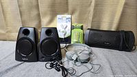Front view of various audio devices including Logitech speakers, headphones, Bluetooth speaker, and packaged accessories