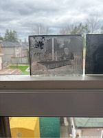 Close-up of an antique glass slide showing a person reclining on a bench with detailed background imagery