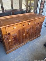 Bottom section of large antique pine hutch showing drawers and paneled doors with round wooden knobs.