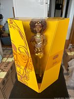 Full front view of Barbie C-3PO doll sealed in yellow packaging