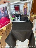 Open view of white hard-shell case revealing styling studio and Barbie doll in two outfits