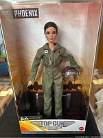 Barbie Top Gun Maverick Phoenix doll displayed in box wearing flight suit, holding helmet inside packaging