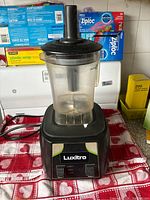 Front view of the Avamix Luxitro juice pulser blender on a countertop, showing control panel with high and low speed buttons and clear container attached.