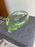 Angled top-down view of the lime green glass candy dish showing its glossy and curved design.