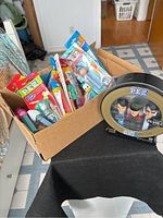 Box filled with assorted vintage PEZ dispensers in plastic packaging showing various characters.