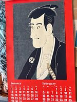 Photo of January and February calendar print with a Japanese ukiyo-e style portrait of a man in traditional clothing against red background with calendar dates