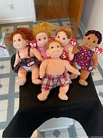 Full set of five vintage Ty Beanie Kids plush dolls arranged on a stand, showing individual dolls and the Ty heart tag on each.
