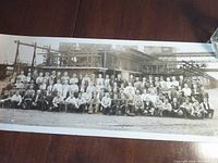 Full view of black and white panoramic photo showing a large group of workers outside industrial coke oven facility.