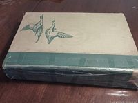 Cover of the Birds of America book, a beige and green hardcover with two illustrated flying birds on the front.