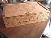 Closed carved wooden storage box showing detailed carved leaf and geometric motifs on top and sides.