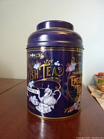 Front view of the large dark blue traditional English tea tin with gold and floral designs.