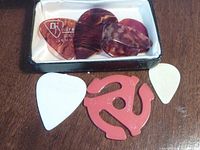Guitar picks shown in detail, including tortoiseshell picks and white picks.