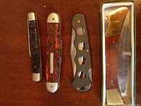 Four pocket knives in closed position showing handles and general wear.