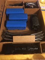 Top view of the Marx train set inside the box showing blue passenger cars, locomotive, track, and transformer parts.