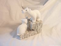 Two white stone polar bear carvings on a rough textured stone base, viewed from the front showing both bears.