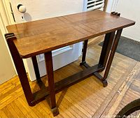 Full view of the 1920's Art Deco wooden table showing the top surface and side design with grouped vertical slats.