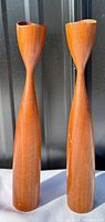 Side view of both wooden teak taper candle holders showing their slender, turned design and warm teak grain.