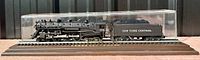 Side view of black Lionel 773 Hudson steam locomotive and tender in clear acrylic display case on a short length of track.