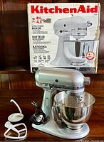 Assembled mixer with bowl and attachments displayed on table in front of original box.