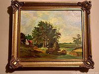 Full view of the framed oil landscape painting showing the gilded ornate frame and overall scene with trees, water, and house.