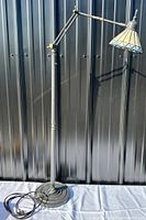 Full view of the Tiffany style slag glass floor lamp showing metal base, adjustable arm, and lamp shade.