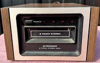 Front view of the vintage Pioneer 8-Track stereo deck showing the tape slot, program numbers 1-4, and branding on a brushed metal and wood grain case.