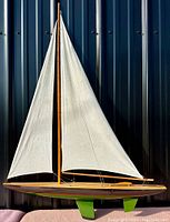 Full view of vintage pond yacht model boat standing upright showing mast, sails, and hull.