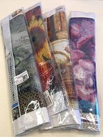 Four rolled and sealed diamond painting kits with visible colorful designs storing beads, canvas, and instructions inside plastic wrapping.
