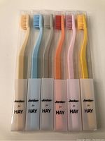 Photo showing six new Jordan for HAY toothbrushes in different pastel colors in plastic protective cases.
