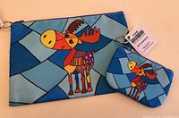 Two fabric items showing patchwork-style colorful moose design on a blue background. Larger pouch and smaller change purse with zippers. Both new with tags.